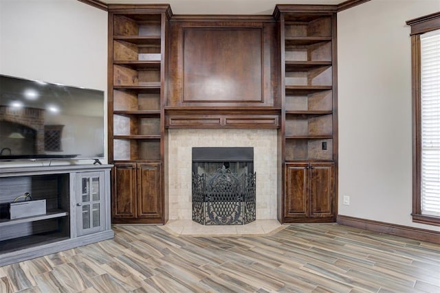 unfurnished living room featuring baseboards, a fireplace with flush hearth, light wood finished floors, and a wealth of natural light
