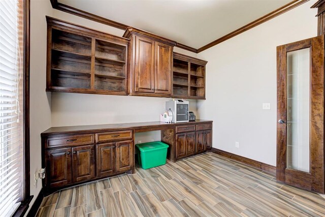 unfurnished office with crown molding, wood finish floors, baseboards, and built in study area