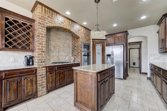 kitchen with backsplash, appliances with stainless steel finishes, arched walkways, light stone counters, and recessed lighting