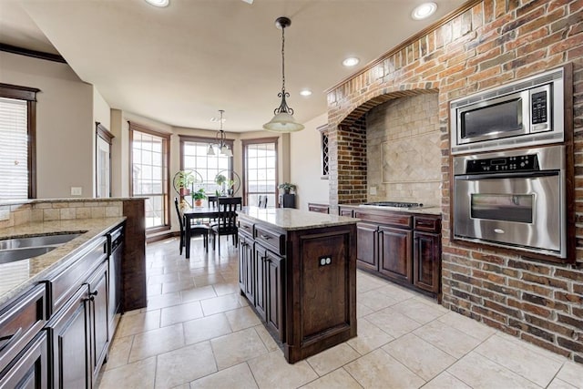 kitchen with hanging light fixtures, light stone countertops, stainless steel appliances, and recessed lighting