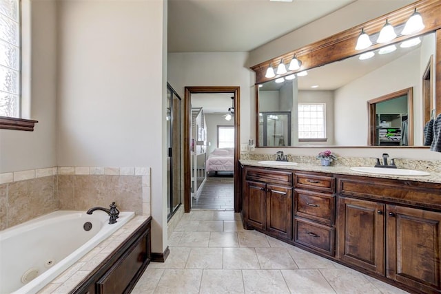 ensuite bathroom featuring a jetted tub, a sink, tile patterned floors, and double vanity