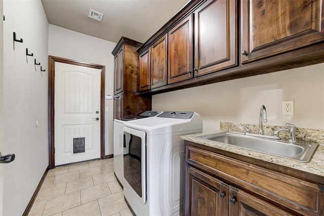washroom featuring visible vents, washing machine and dryer, baseboards, a sink, and cabinet space