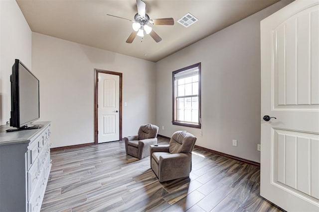 sitting room featuring ceiling fan, visible vents, baseboards, and light wood finished floors