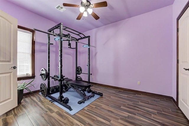 exercise area with visible vents, a ceiling fan, baseboards, and wood finished floors