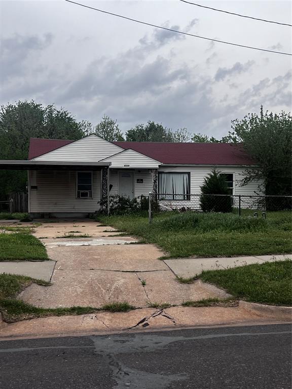 view of front of property featuring concrete driveway, a fenced front yard, and a carport