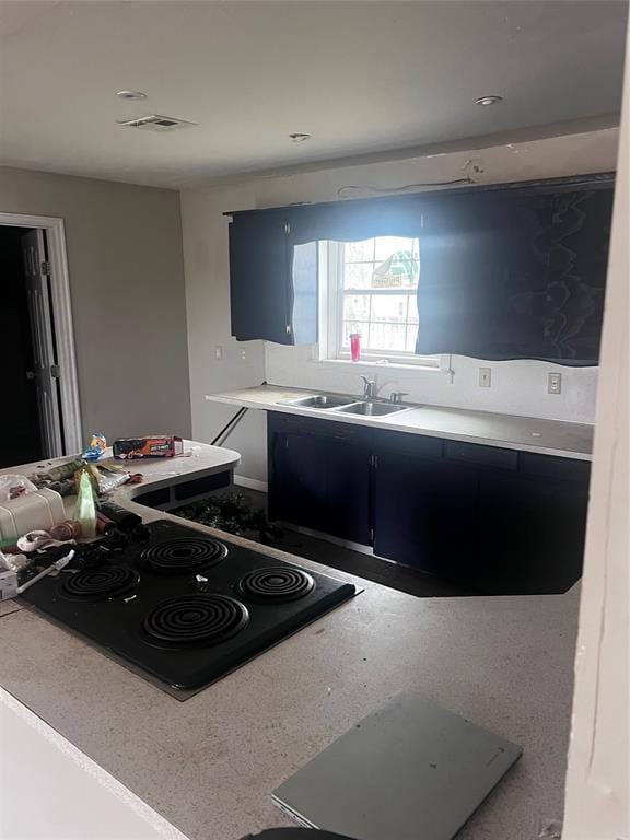 kitchen featuring a sink, visible vents, stove, light countertops, and dark cabinetry