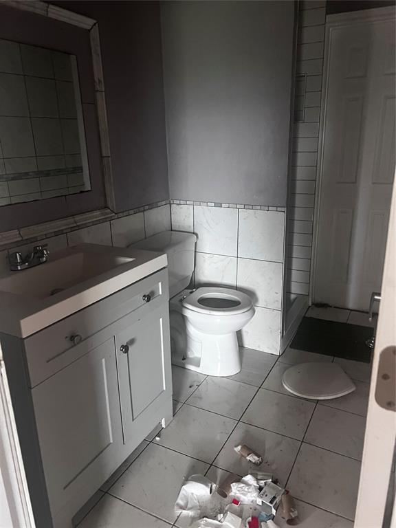 bathroom with toilet, tile walls, and vanity