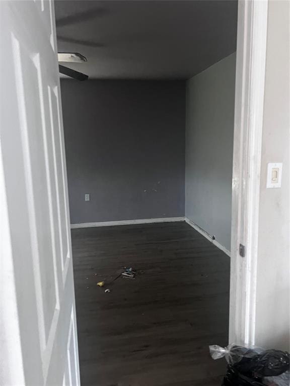unfurnished room with ceiling fan, baseboards, and dark wood-style floors