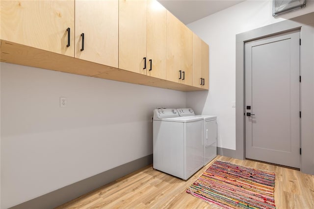 laundry room featuring cabinet space, baseboards, light wood finished floors, and washing machine and clothes dryer