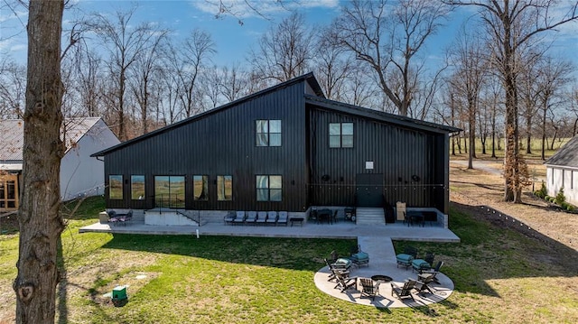 rear view of property featuring a patio, a yard, and an outdoor fire pit