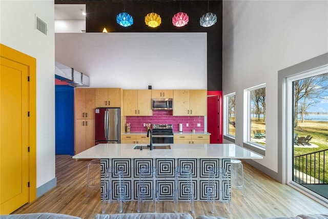 kitchen featuring light countertops, stainless steel appliances, light wood-style flooring, and visible vents