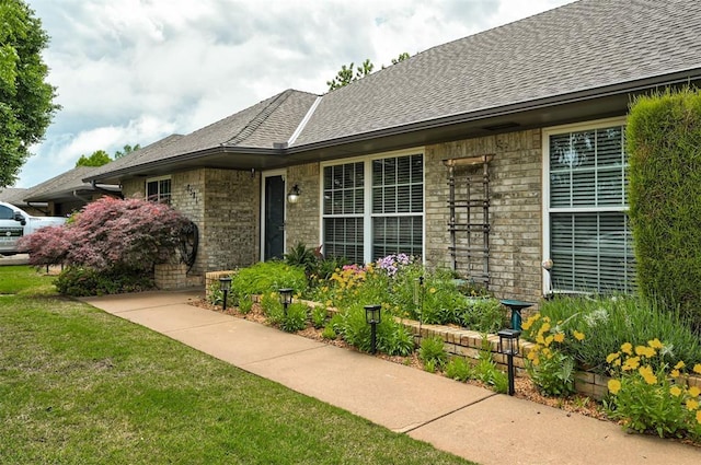property entrance with a yard and roof with shingles