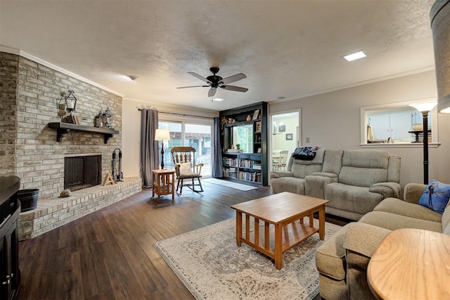 living area featuring crown molding, ceiling fan, a brick fireplace, a textured ceiling, and wood finished floors