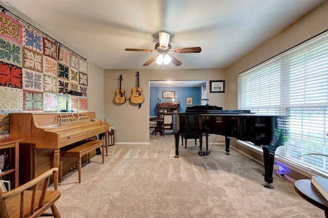 sitting room featuring plenty of natural light, a ceiling fan, baseboards, and light carpet