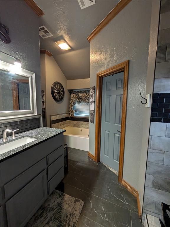 900 Walnut Pl, Norman, OK 73072 - full bathroom with lofted ceiling, a bath, vanity, a textured wall, and marble finish floors