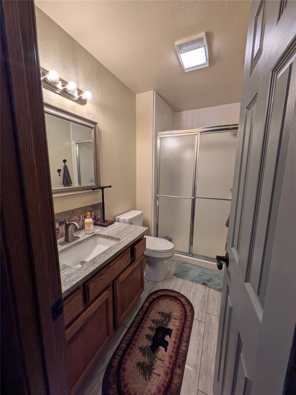 900 Walnut Pl, Norman, OK 73072 - bathroom featuring a shower stall, vanity, toilet, and a textured wall