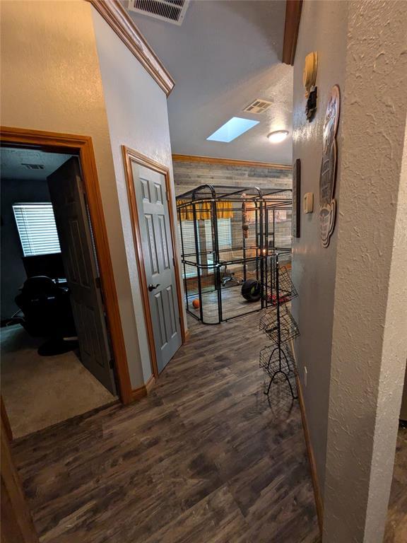 900 Walnut Pl, Norman, OK 73072 - corridor featuring a textured wall, wood finished floors, a skylight, and baseboards