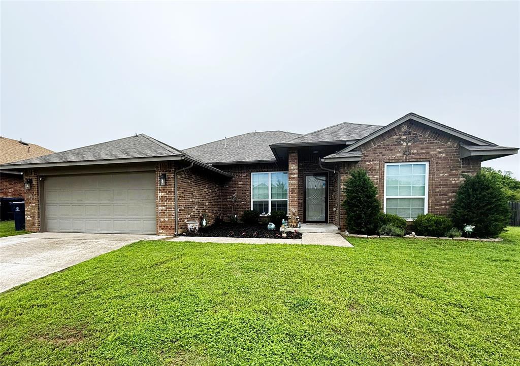view of front of home with a front yard, brick siding, a shingled roof, concrete driveway, and an attached garage