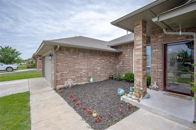 1208 Hickory Creek Dr, Yukon, OK 73099 - view of property exterior with a shingled roof, brick siding, driveway, and a garage