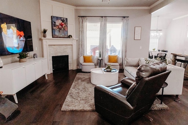 living room with dark wood-style flooring, visible vents, crown molding, a fireplace, and a chandelier