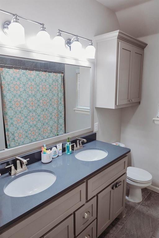 bathroom with a shower with shower curtain, double vanity, toilet, and a sink