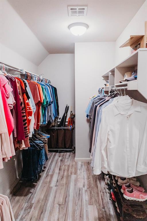 walk in closet with vaulted ceiling, wood finished floors, and visible vents
