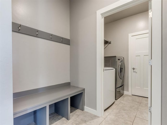clothes washing area featuring separate washer and dryer, baseboards, laundry area, and light tile patterned flooring
