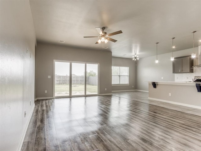 unfurnished living room with baseboards, ceiling fan, wood finished floors, and visible vents
