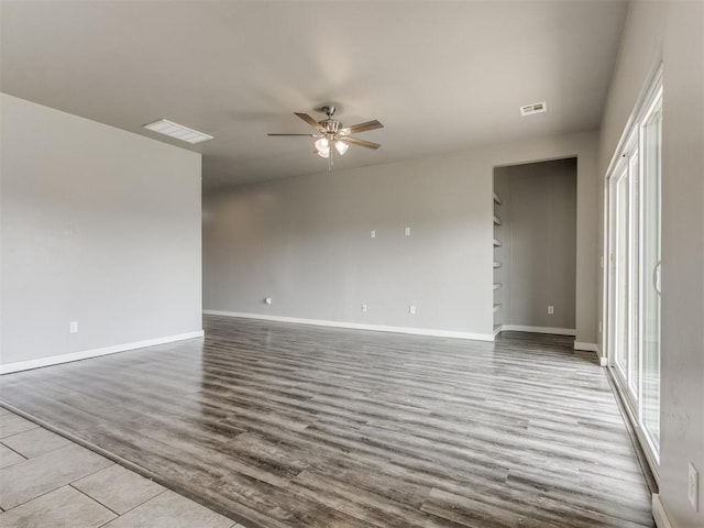 spare room featuring visible vents, a ceiling fan, and baseboards