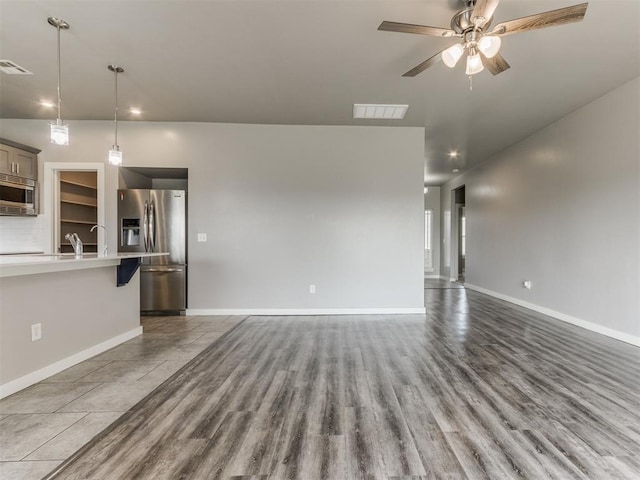 unfurnished living room featuring baseboards, ceiling fan, visible vents, and wood finished floors
