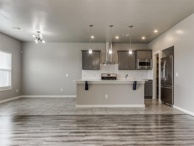 kitchen featuring appliances with stainless steel finishes, light countertops, wall chimney exhaust hood, tasteful backsplash, and visible vents