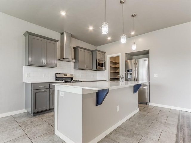 kitchen with gray cabinetry, tasteful backsplash, wall chimney range hood, and stainless steel appliances