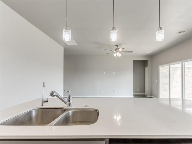 kitchen with a sink, a ceiling fan, open floor plan, decorative light fixtures, and visible vents