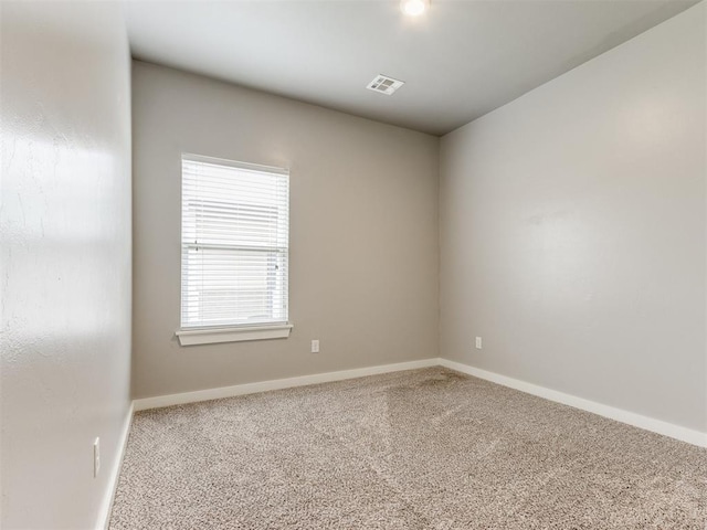 carpeted spare room featuring baseboards and visible vents