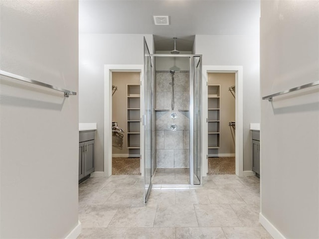 bathroom with vanity, baseboards, a stall shower, and visible vents