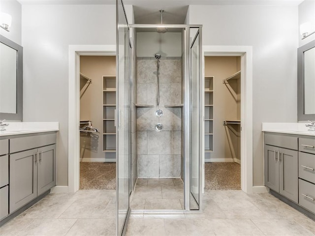 full bathroom with a sink, tile patterned floors, baseboards, two vanities, and a shower stall