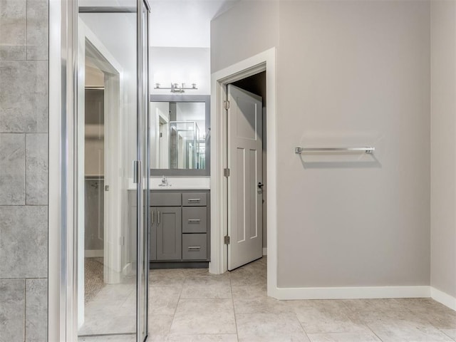 bathroom featuring a walk in closet, baseboards, tile patterned floors, and vanity