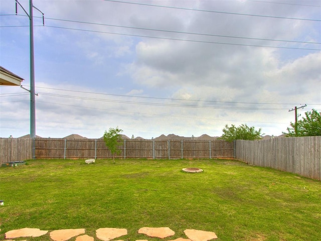view of yard featuring a fenced backyard and a fire pit