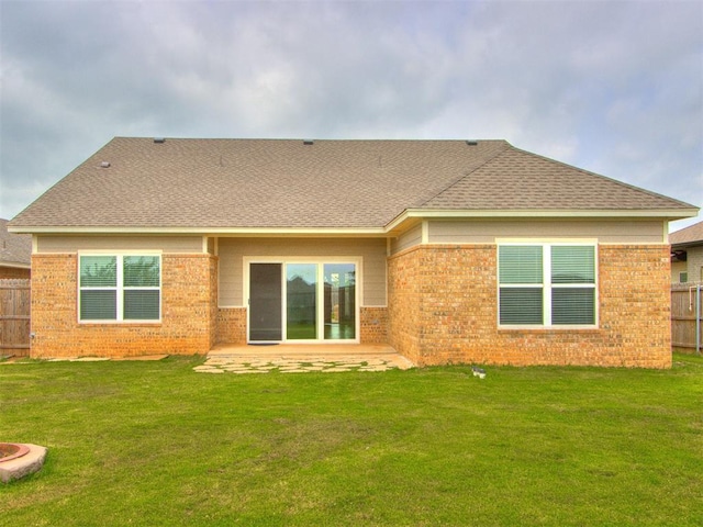 rear view of house featuring fence, a shingled roof, and brick siding