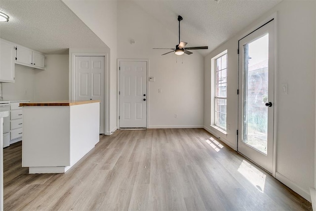 unfurnished living room with a ceiling fan, a textured ceiling, vaulted ceiling, baseboards, and light wood-style flooring