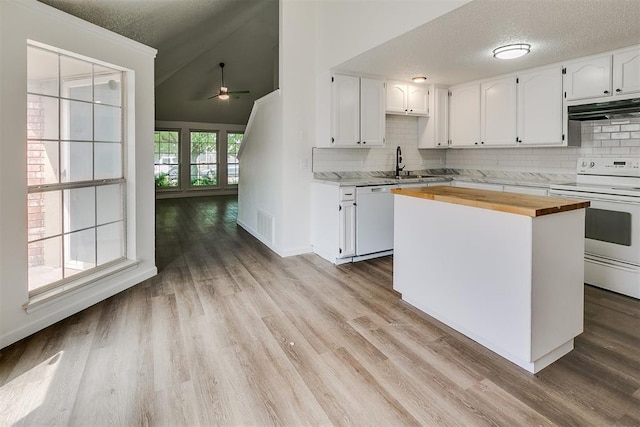 kitchen featuring white appliances, white cabinetry, backsplash, under cabinet range hood, and butcher block counters