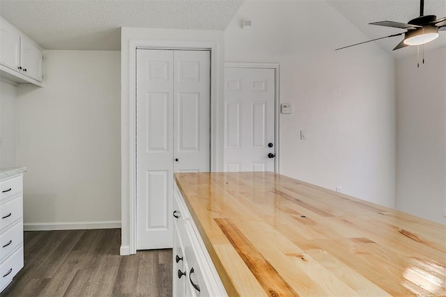 interior space featuring white cabinets, ceiling fan, a textured ceiling, butcher block countertops, and dark wood finished floors