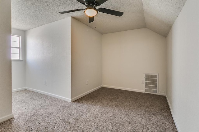 carpeted empty room with ceiling fan, lofted ceiling, a textured ceiling, and visible vents
