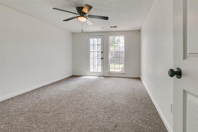 carpeted spare room featuring visible vents, a ceiling fan, a textured ceiling, and baseboards