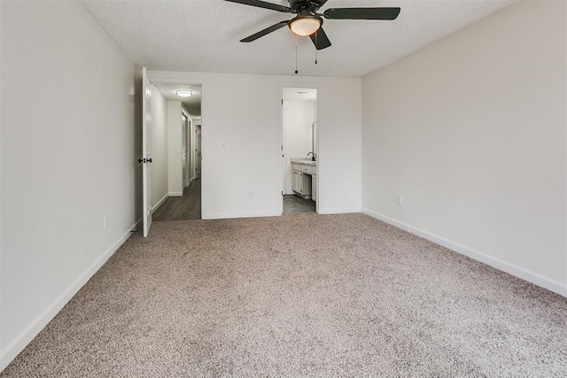 unfurnished bedroom with carpet floors, baseboards, ceiling fan, and ensuite bath