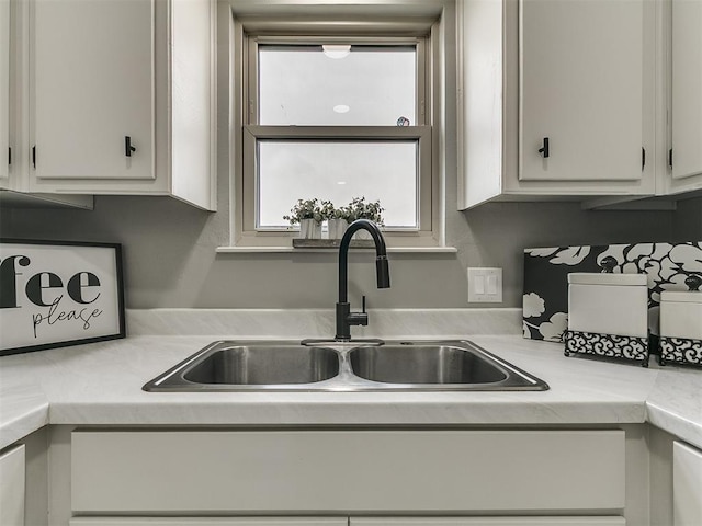 kitchen with a sink, light countertops, and white cabinets