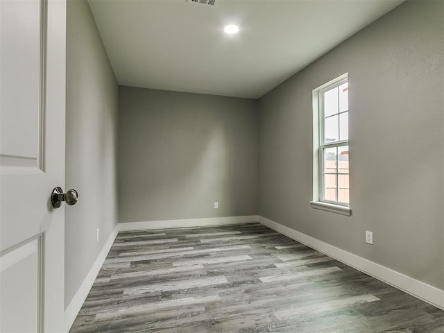 empty room with baseboards, visible vents, and wood finished floors