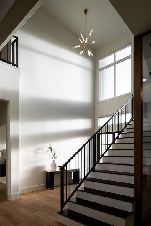 2826 Guilford Ln, Oklahoma City, OK 73120 - staircase with a chandelier, wood finished floors, baseboards, and a towering ceiling