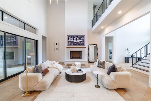 2826 Guilford Ln, Oklahoma City, OK 73120 - living room with a towering ceiling, stairs, wood finished floors, a fireplace with raised hearth, and baseboards