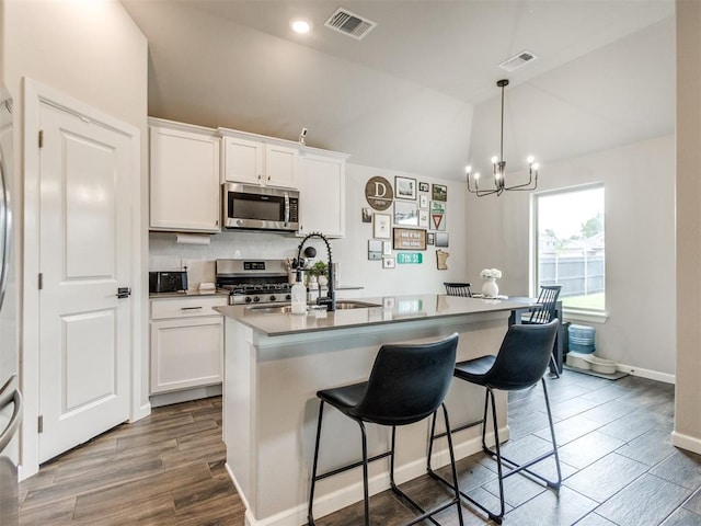 kitchen featuring white cabinets, lofted ceiling, a chandelier, and stainless steel appliances